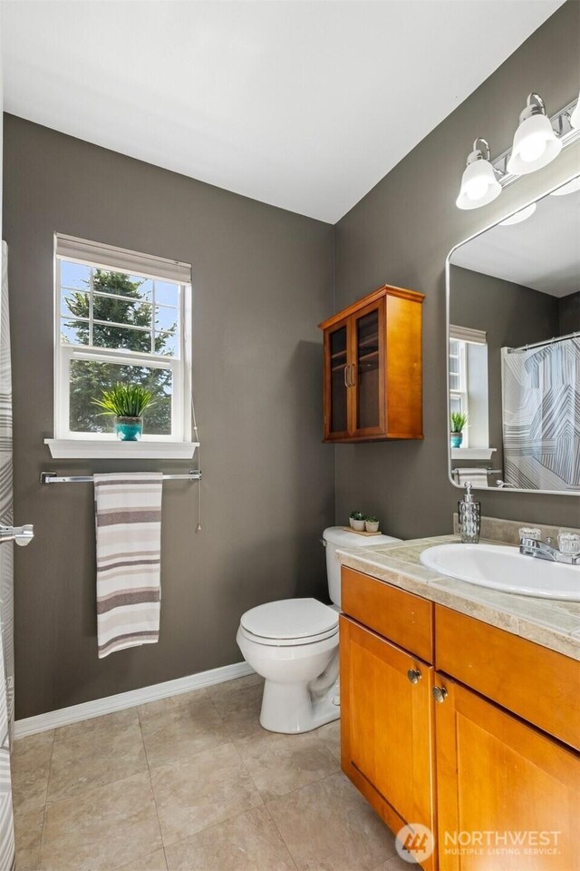 bathroom with toilet, vanity, tile patterned flooring, and baseboards