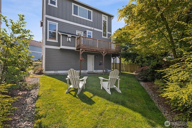 rear view of house featuring board and batten siding, a wooden deck, and a yard