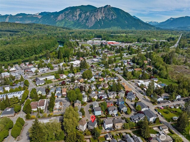 aerial view of property's location featuring a mountainous background, a forest, and nearby suburban area