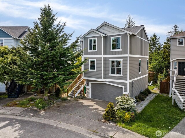 view of front of home with stairway, board and batten siding, driveway, a garage, and stone siding