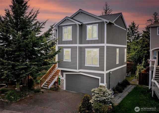 view of front facade featuring board and batten siding, stairs, driveway, a garage, and fence