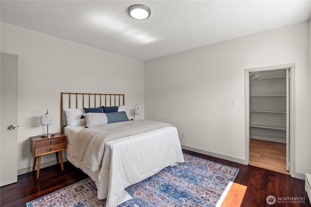 506 G St, Cosmopolis, WA 98537 - bedroom featuring wood finished floors, a spacious closet, a textured ceiling, baseboards, and baseboard heating