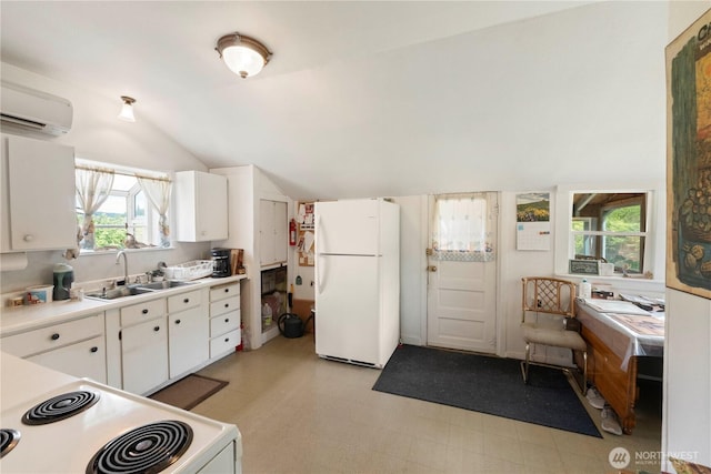 kitchen with white appliances, a sink, a wall mounted AC, lofted ceiling, and white cabinetry