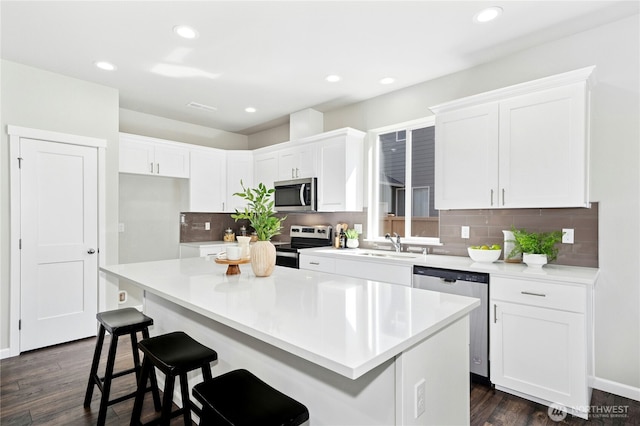 16636 8th Avenue Ct E Unit 05, Spanaway, WA 98387 - kitchen featuring appliances with stainless steel finishes, white cabinets, a center island, dark wood-style floors, and decorative backsplash