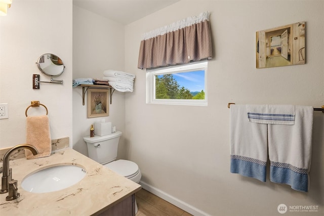bathroom featuring toilet, baseboards, vanity, and wood finished floors
