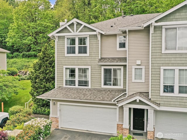 craftsman house featuring an attached garage, stone siding, roof with shingles, and asphalt driveway