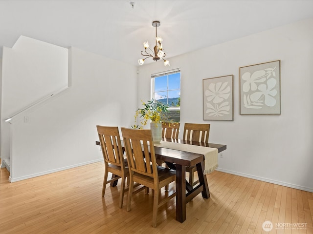 dining space featuring a chandelier, light wood-style flooring, and baseboards