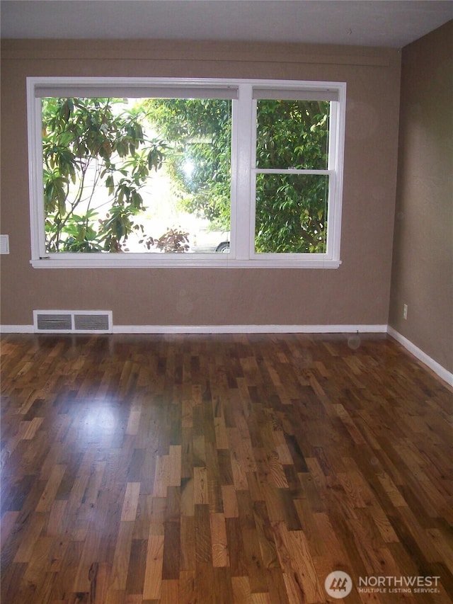 spare room featuring baseboards and wood finished floors