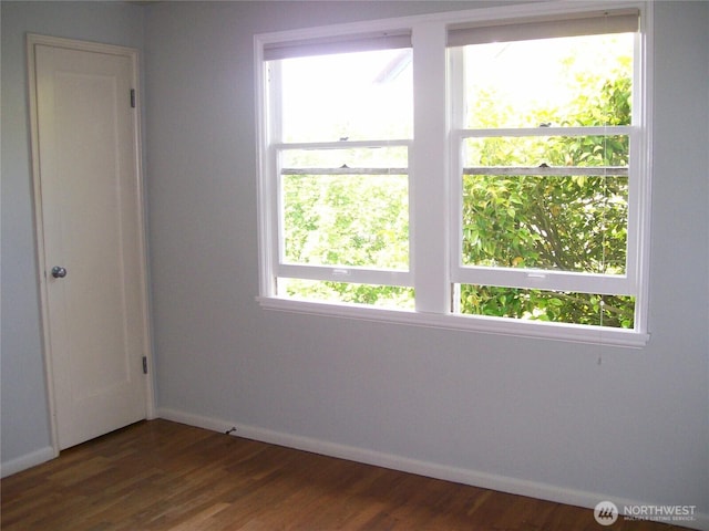 spare room with baseboards and dark wood finished floors