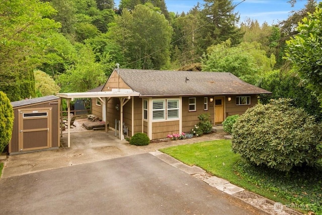304 Riverview Dr NE, Auburn, WA 98002 - view of front of property featuring asphalt driveway, a storage unit, a carport, a forest view, and an outdoor structure