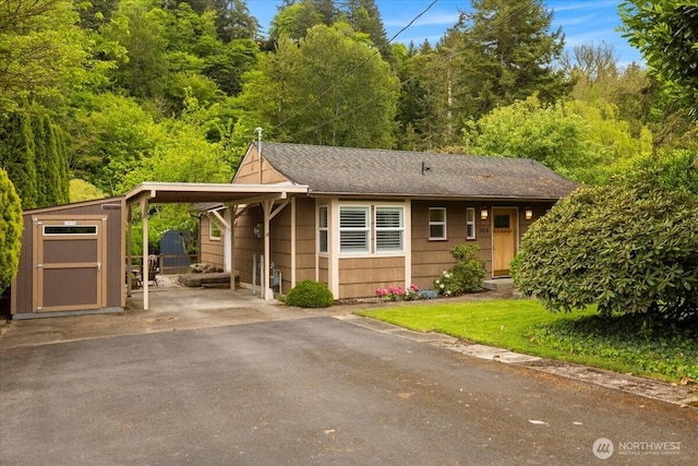 304 Riverview Dr NE, Auburn, WA 98002 - view of front of house with a storage shed, an outdoor structure, asphalt driveway, an attached carport, and roof with shingles