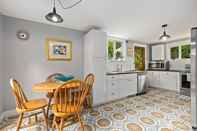 304 Riverview Dr NE, Auburn, WA 98002 - kitchen with stainless steel appliances, tasteful backsplash, a sink, dark countertops, and white cabinetry