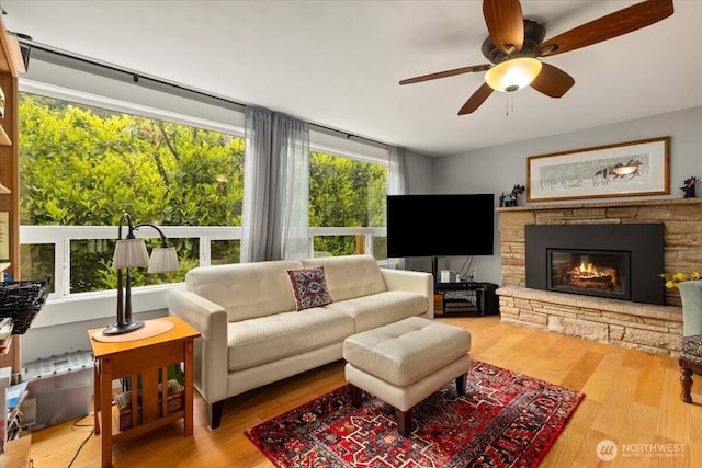304 Riverview Dr NE, Auburn, WA 98002 - living area featuring wood finished floors, a ceiling fan, and a stone fireplace