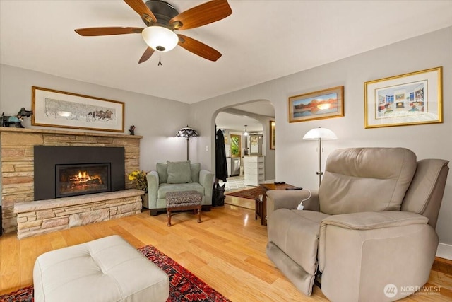 304 Riverview Dr NE, Auburn, WA 98002 - living room featuring arched walkways, ceiling fan, light wood-style flooring, and a stone fireplace