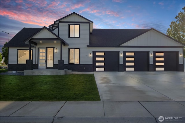 view of front facade with a garage, a lawn, concrete driveway, board and batten siding, and a shingled roof