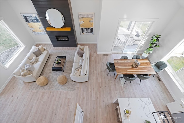 living room featuring a large fireplace, wood finished floors, and baseboards
