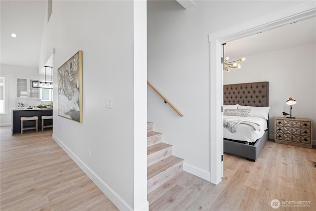 stairway with a chandelier, wood finished floors, and baseboards
