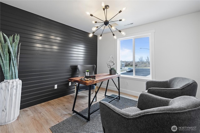 office space featuring a chandelier, wood finished floors, baseboards, and an accent wall