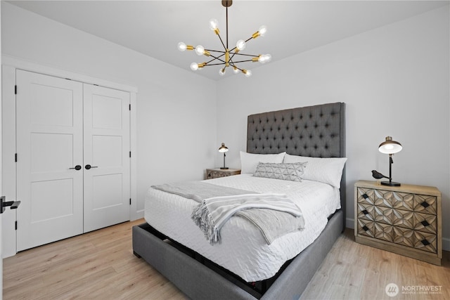 bedroom featuring a chandelier, light wood-type flooring, a closet, and baseboards