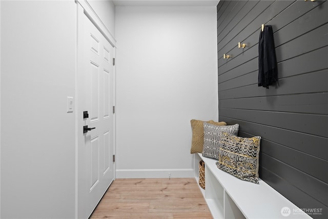 mudroom featuring light wood-style flooring, wood walls, and baseboards