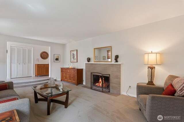 living room with a premium fireplace, baseboards, and light carpet