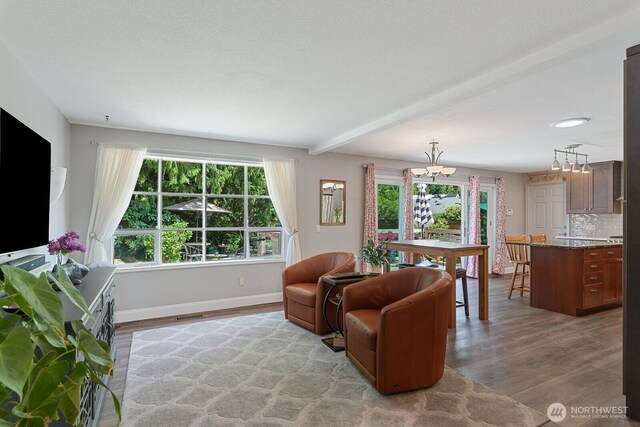 living room featuring a chandelier, wood finished floors, baseboards, and beamed ceiling