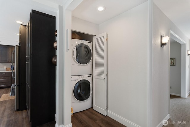 washroom featuring estacked washer and dryer, baseboards, dark wood-type flooring, and recessed lighting