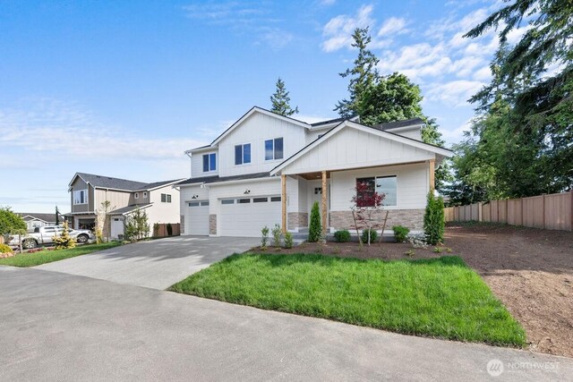 7332 284th St NW, Stanwood, WA 98292 - view of front facade with an attached garage, board and batten siding, concrete driveway, stone siding, and covered porch