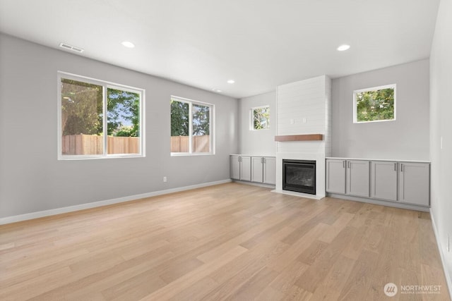 7332 284th St NW, Stanwood, WA 98292 - unfurnished living room with light wood finished floors, a fireplace, and recessed lighting