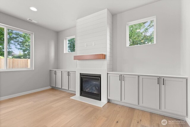 7332 284th St NW, Stanwood, WA 98292 - unfurnished living room featuring light wood-type flooring, a glass covered fireplace, and recessed lighting