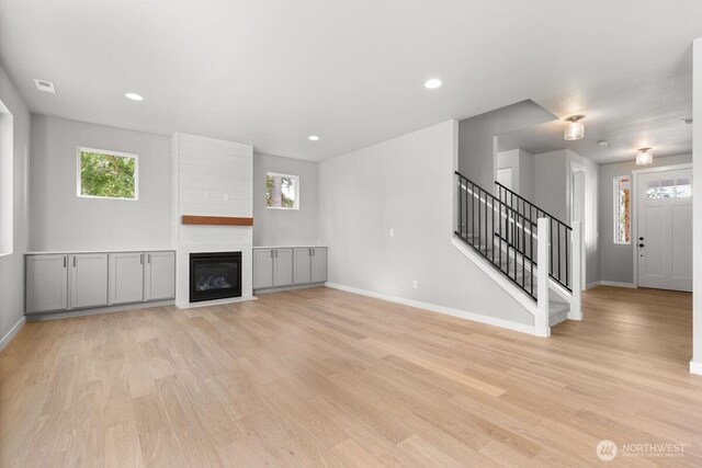7332 284th St NW, Stanwood, WA 98292 - unfurnished living room with stairs, light wood finished floors, a large fireplace, and recessed lighting