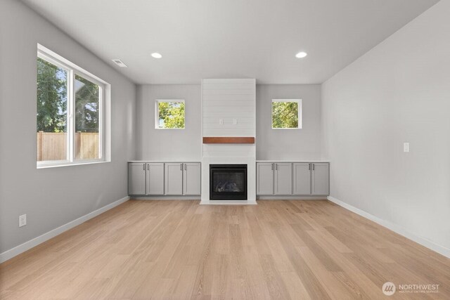 7332 284th St NW, Stanwood, WA 98292 - unfurnished living room featuring plenty of natural light, light wood-style flooring, a fireplace, and recessed lighting
