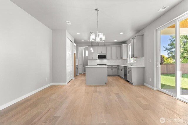 7332 284th St NW, Stanwood, WA 98292 - kitchen with gray cabinets, appliances with stainless steel finishes, a chandelier, a kitchen island, and light wood finished floors