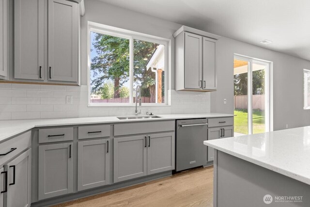 7332 284th St NW, Stanwood, WA 98292 - kitchen with dishwasher, gray cabinets, backsplash, light wood-style floors, and light stone counters