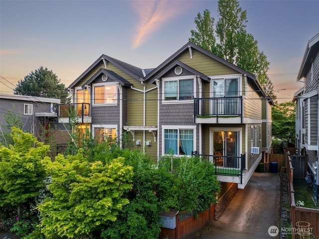 back of property at dusk featuring a balcony and central AC