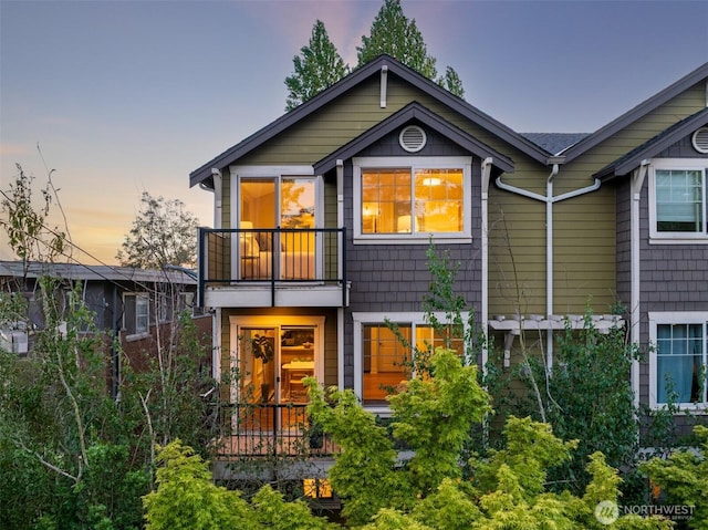 back of house at dusk with a balcony