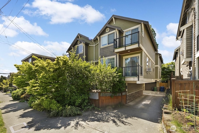 view of front of house with a balcony, fence, cooling unit, central AC, and driveway