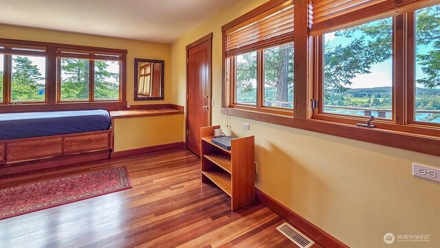 bedroom with multiple windows, light wood finished floors, and baseboards