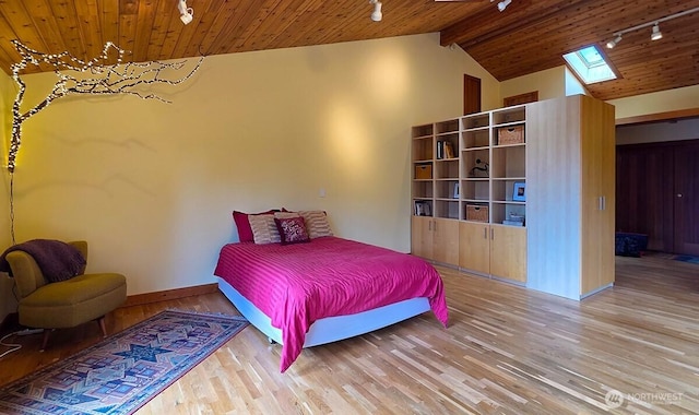 bedroom with rail lighting, wood ceiling, a skylight, wood finished floors, and baseboards