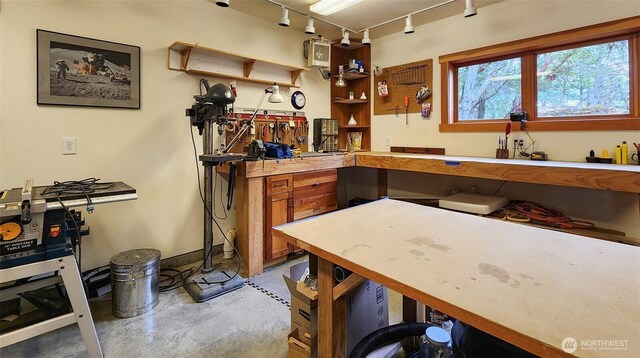 bar area featuring rail lighting, a workshop area, and concrete flooring