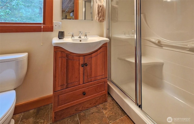 bathroom with toilet, a shower with door, vanity, and stone finish flooring