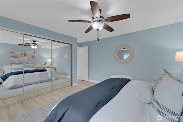 bedroom with wood finished floors, a closet, baseboards, and ceiling fan