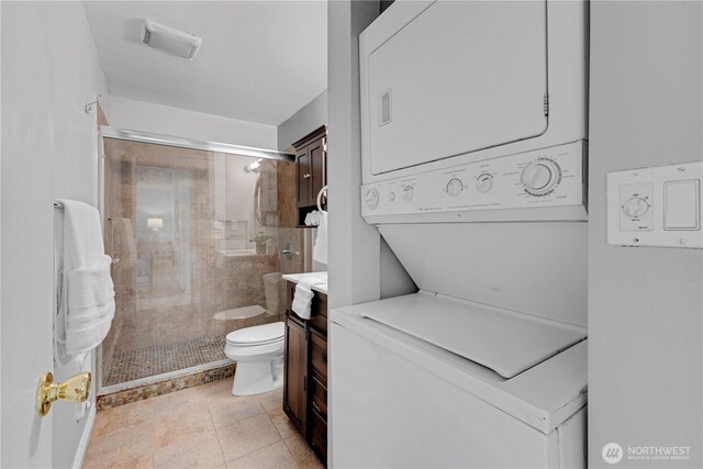bathroom with stacked washer / drying machine, toilet, a shower stall, and vanity