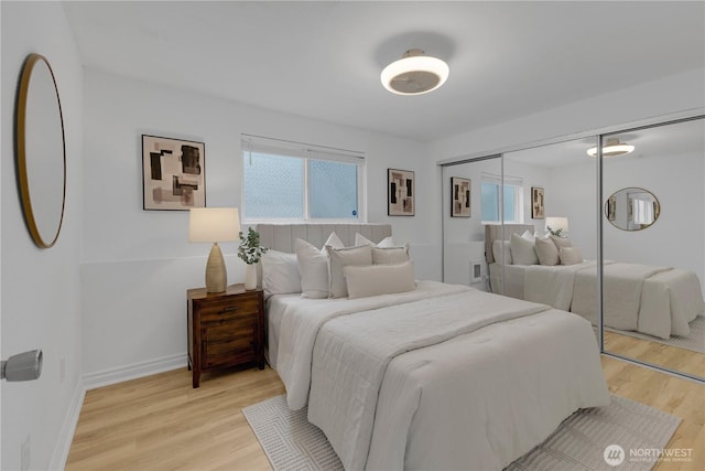 bedroom featuring light wood-style flooring, multiple windows, and a closet