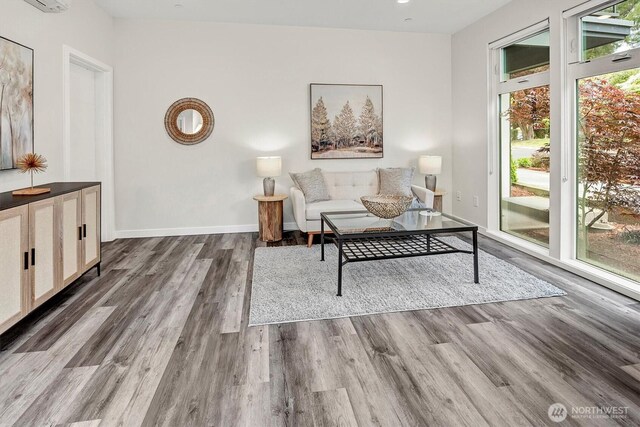 living area featuring dark wood-type flooring, baseboards, and a wall unit AC