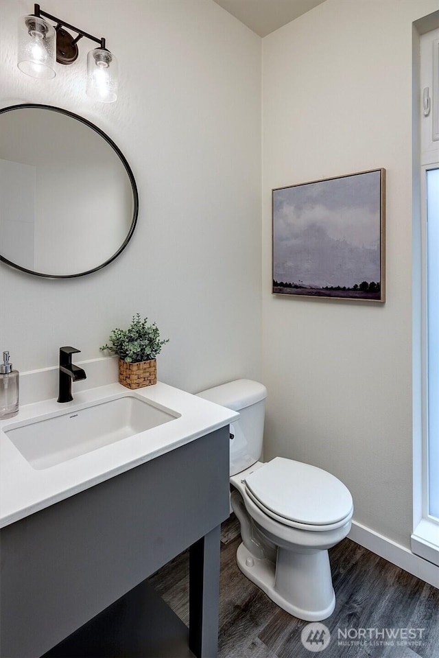 bathroom with wood finished floors, a sink, toilet, and baseboards