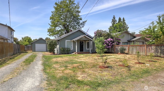bungalow-style house featuring driveway, a detached garage, an outbuilding, and a porch