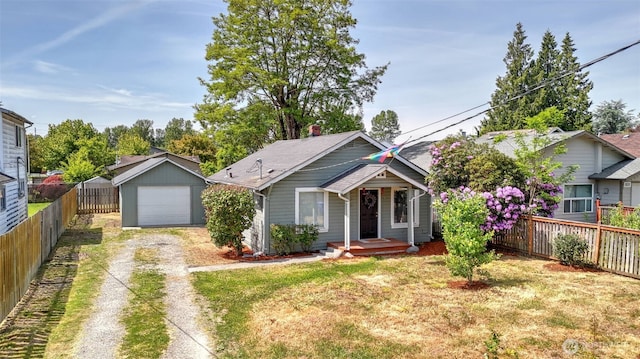 bungalow with dirt driveway, a garage, and an outdoor structure