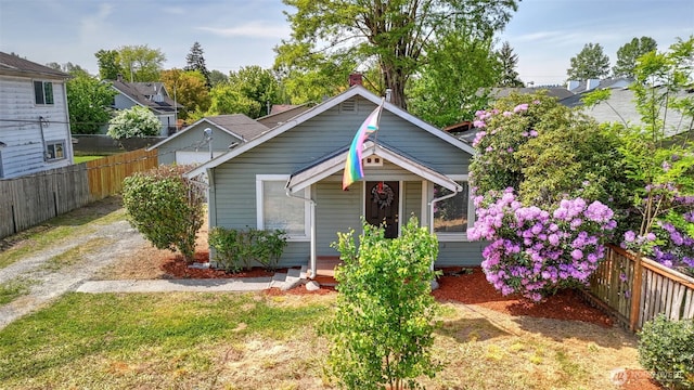 bungalow-style house with fence, a chimney, and a porch