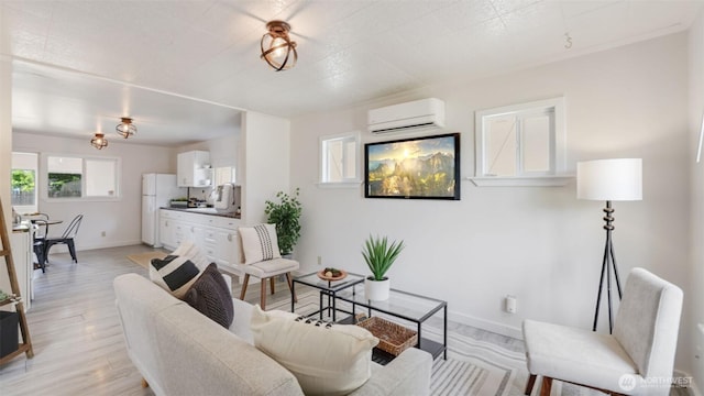 living area with a wall mounted air conditioner, light wood finished floors, and baseboards